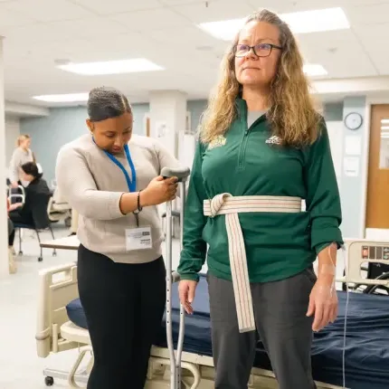 A P T student practices measuring a crutch for a patient